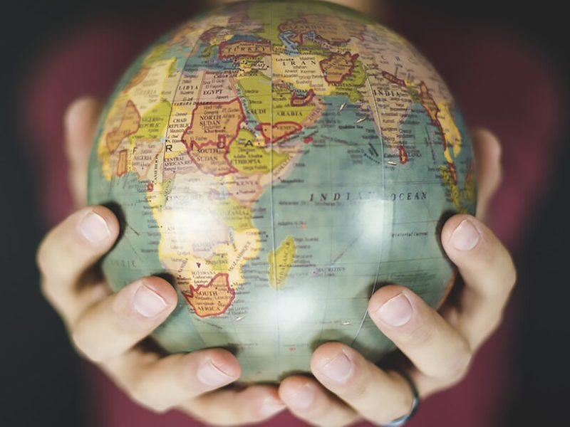 A-person-gently-cradles-a-small-globe-in-both-hands-symbolizing-a-deep-connection-to-the-world
